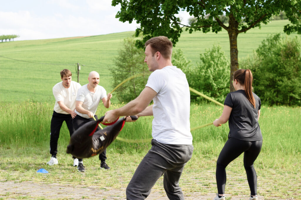 Gruppe macht Zirkeltraining draußen mit verschiedenen Geräten